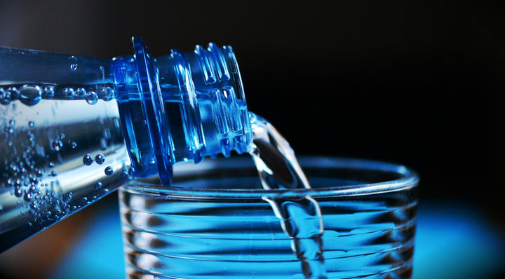 close-up of bottle pouring water on glass