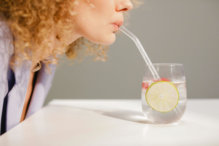 woman drinking out of a glass straw